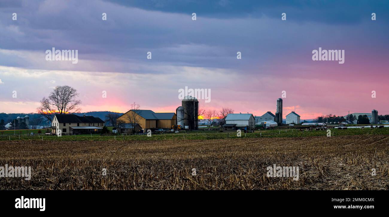 Blick auf Sonnenuntergang, Roten Himmel und Sonne, mit Wolken, die die Aussicht versperren, wie ein Feuer in der Ferne, mit Blick auf eine Farm und Ackerland Stockfoto