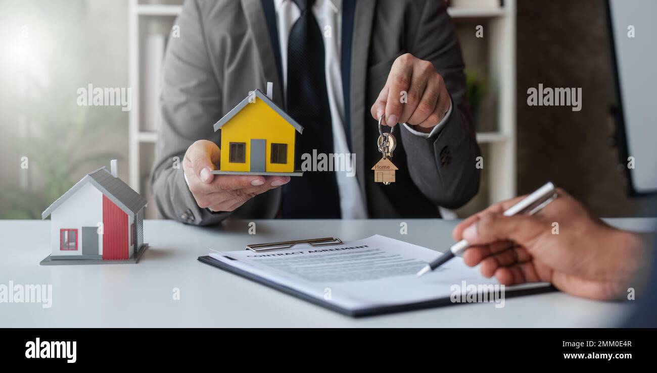 Nahaufnahme des Immobilienmaklers, um Häuser und Grundstücke zu kaufen, liefern Schlüssel und Häuser. Gespräch mit einem Immobilienmakler Stockfoto