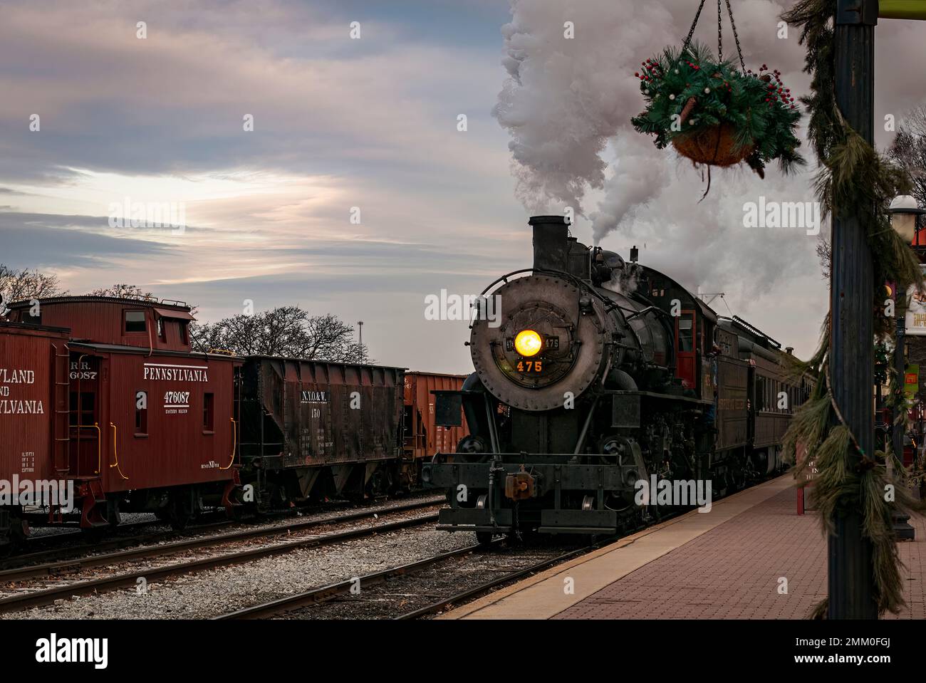 Strasburg, Pennsylvania, 27. Dezember 2022 - A View of a Classic Steam Passenger Train Arrival in a Train Station Blowing Smoke and Steam, an einem Wintertag Stockfoto