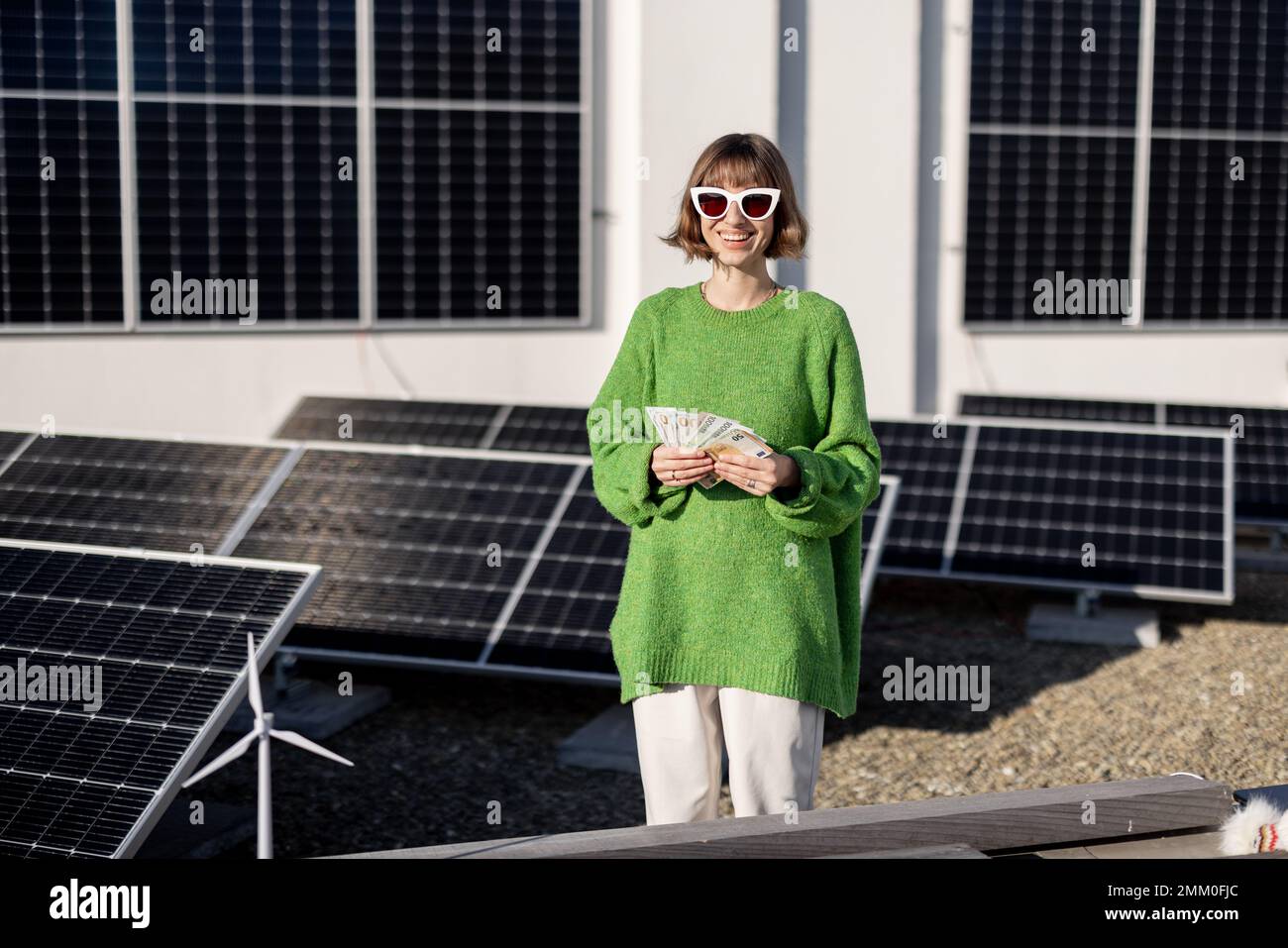 Frau zählt Euro-Banknoten in der Nähe eines Solarkraftwerks Stockfoto