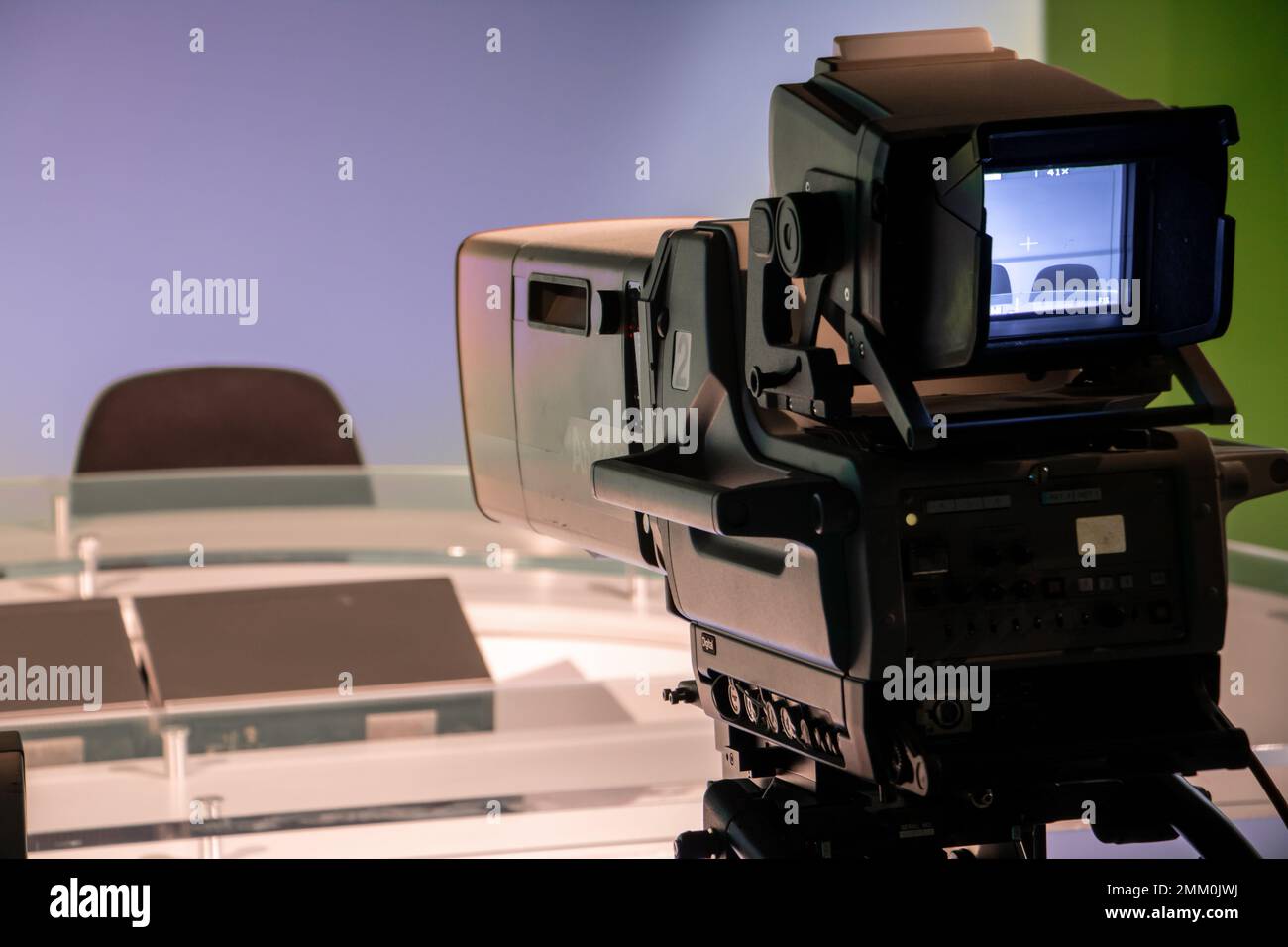 TV-Studio mit professioneller Kamera, die auf einen leeren Sitz zielt, Fokus auf die Kamera. Stockfoto