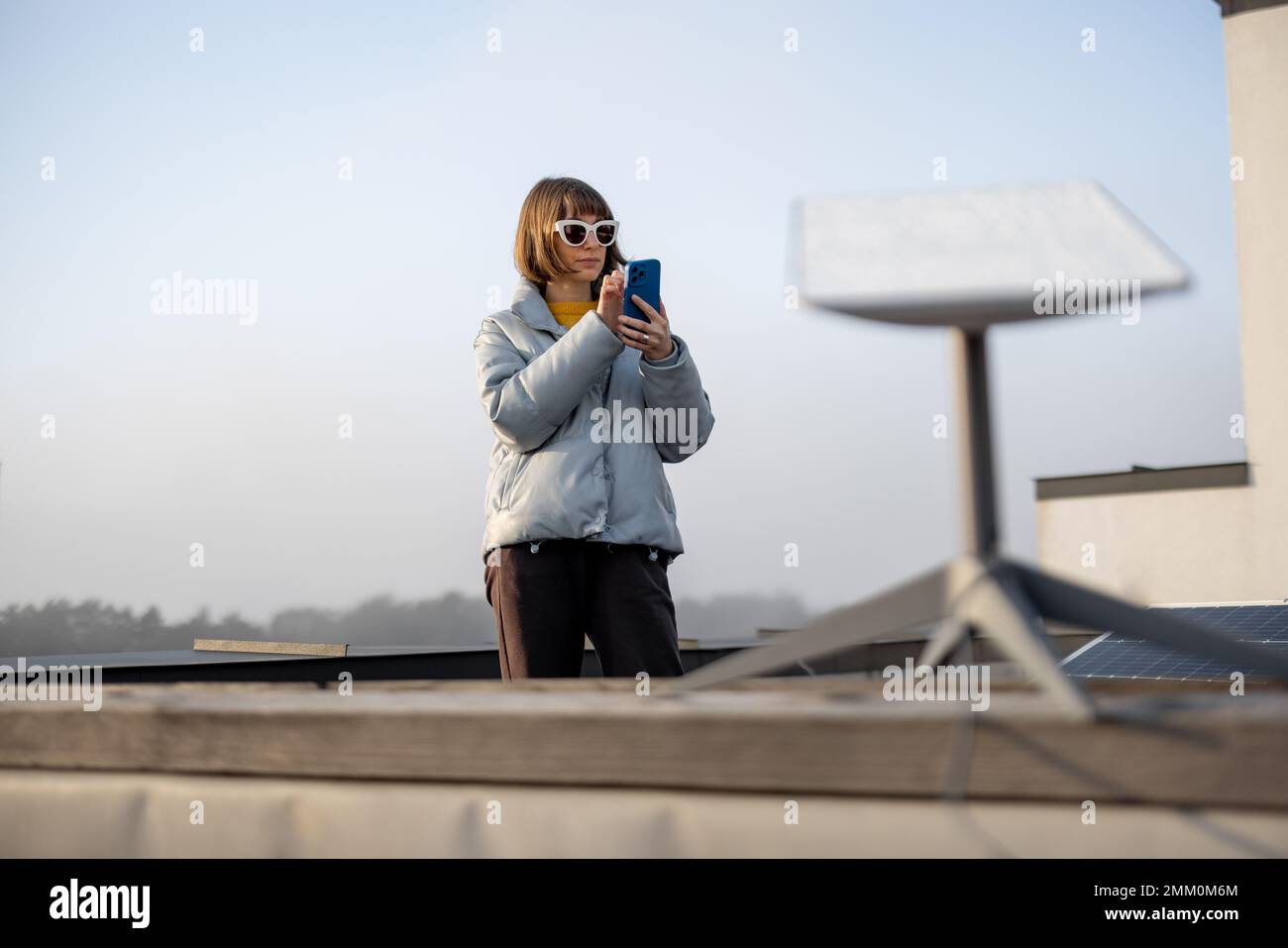 Frau nutzt Satelliten-Internetverbindung auf dem Dach eines Hauses Stockfoto