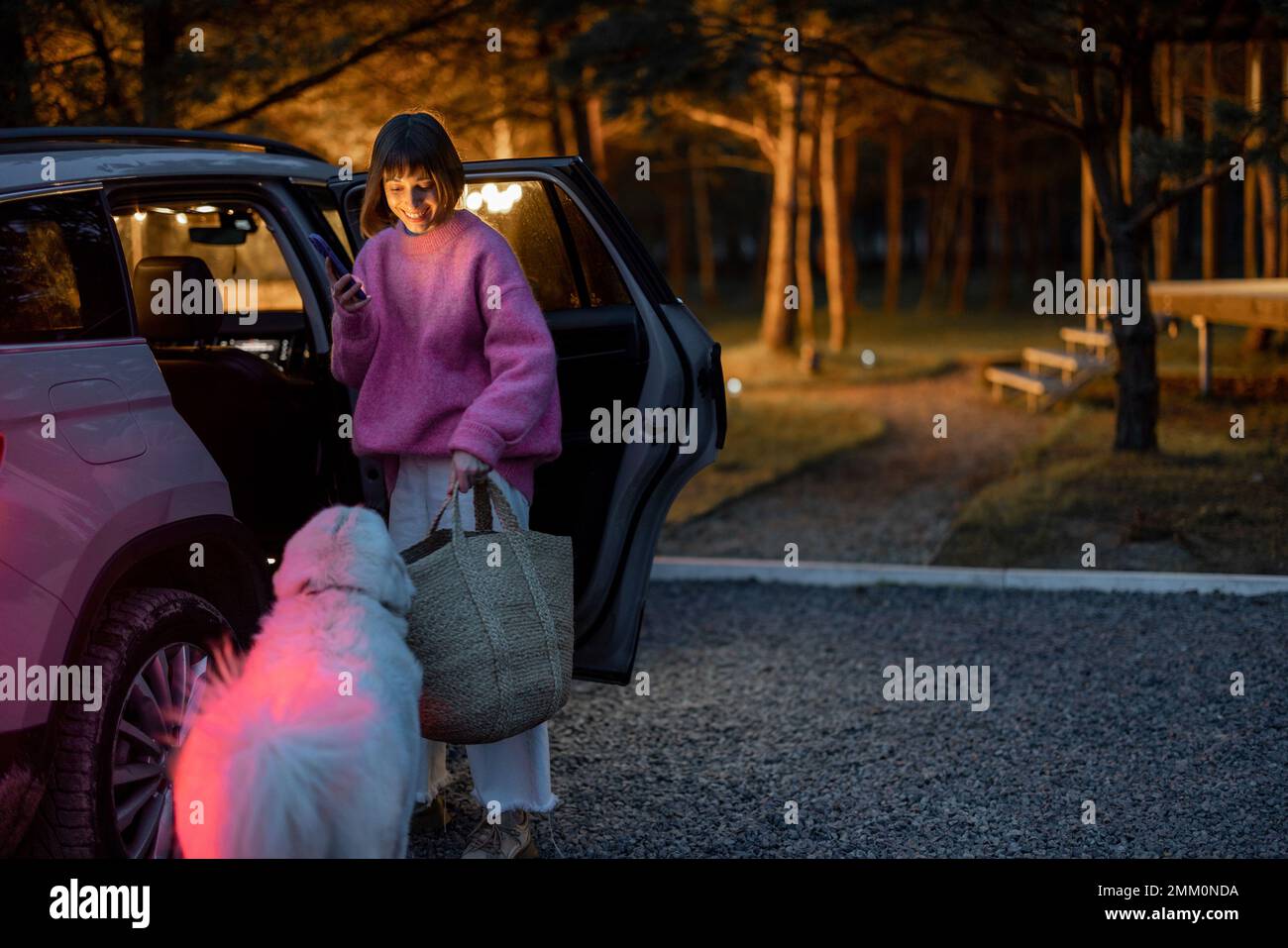 Eine Frau kommt mit dem Auto zu einem Haus im Wald Stockfoto