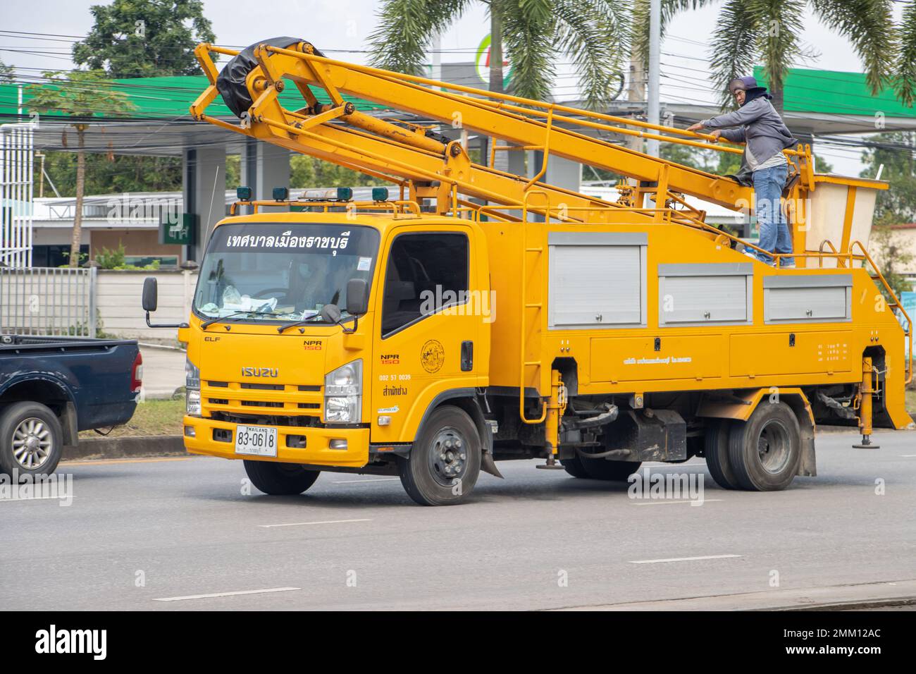 RATCHABURI, THAILAND, NOV. 16 2022, fährt Ein Lkw mit einer Hebebühne die Straße hinunter mit Arbeiter oben Stockfoto