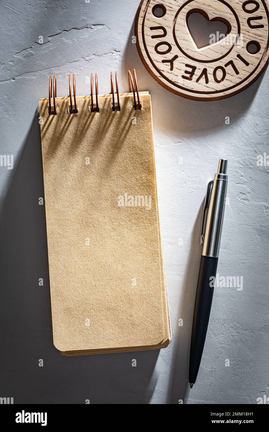 Kraftnotizbuch und klassischer Stift auf dem Schreibtisch. Valentinstagskonzept Stockfoto