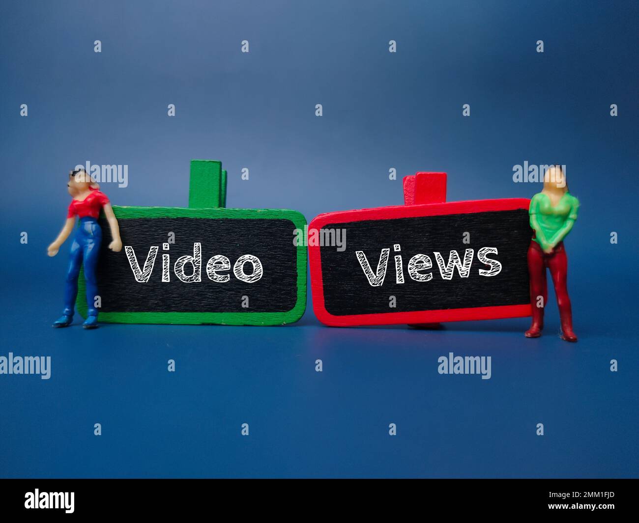 Miniaturmenschen und Holztafel mit dem Wort VIDEO VIEWS auf blauem Hintergrund. Stockfoto