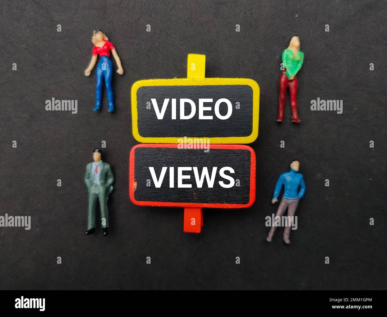 Miniaturmenschen und Holztafel mit dem Wort "VIDEO VIEWS" auf schwarzem Hintergrund. Stockfoto