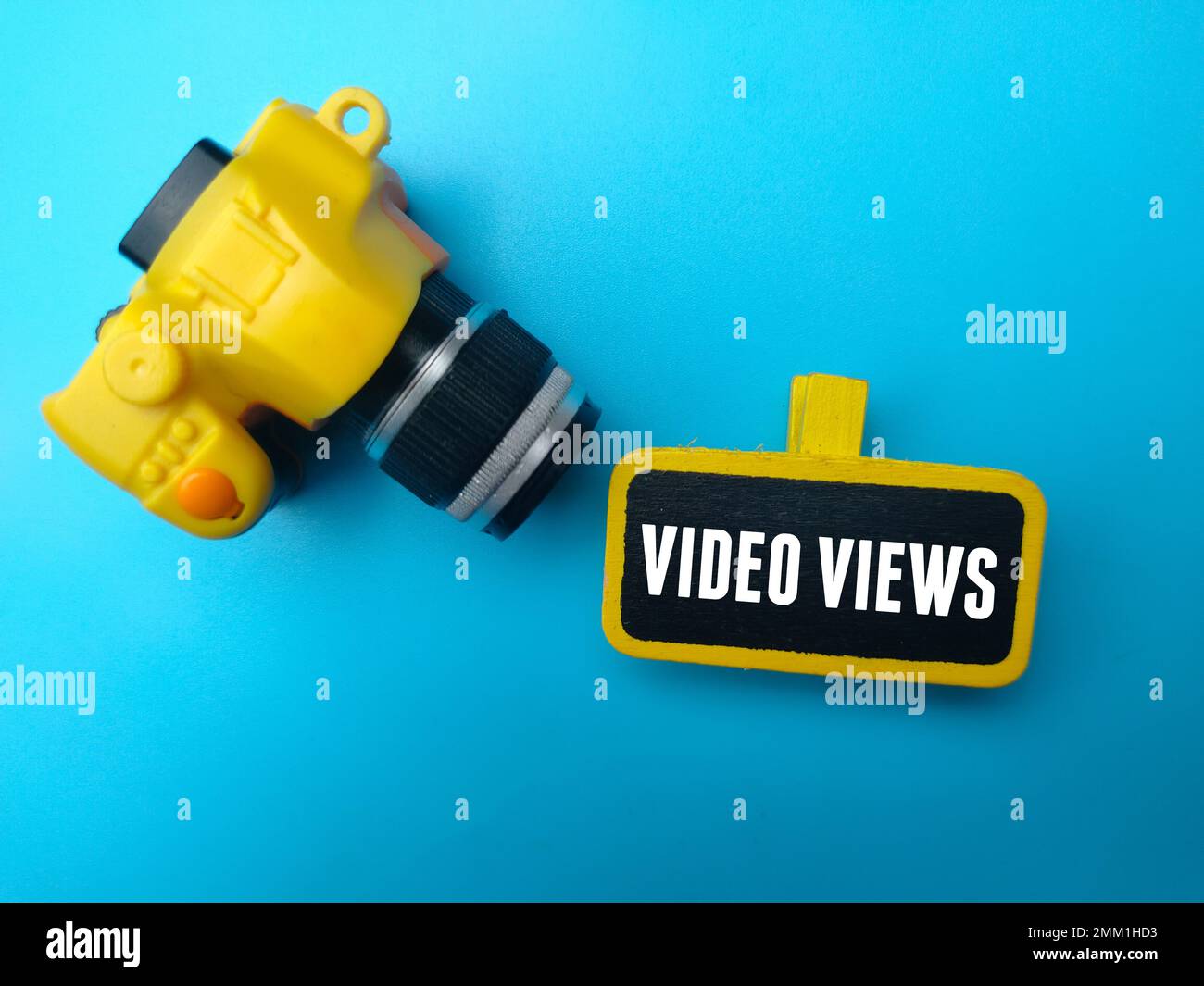Gelbe Kamera und Holzbrett mit dem Wort VIDEO VIEWS auf blauem Hintergrund. Stockfoto