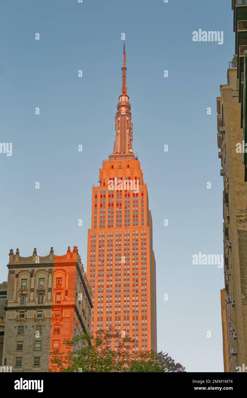 NYC: Die östliche Fassade des Empire State Building verläuft bei Sonnenaufgang von grau bis goldrot, wenn die Sonne am tiefsten Punkt steht. Stockfoto