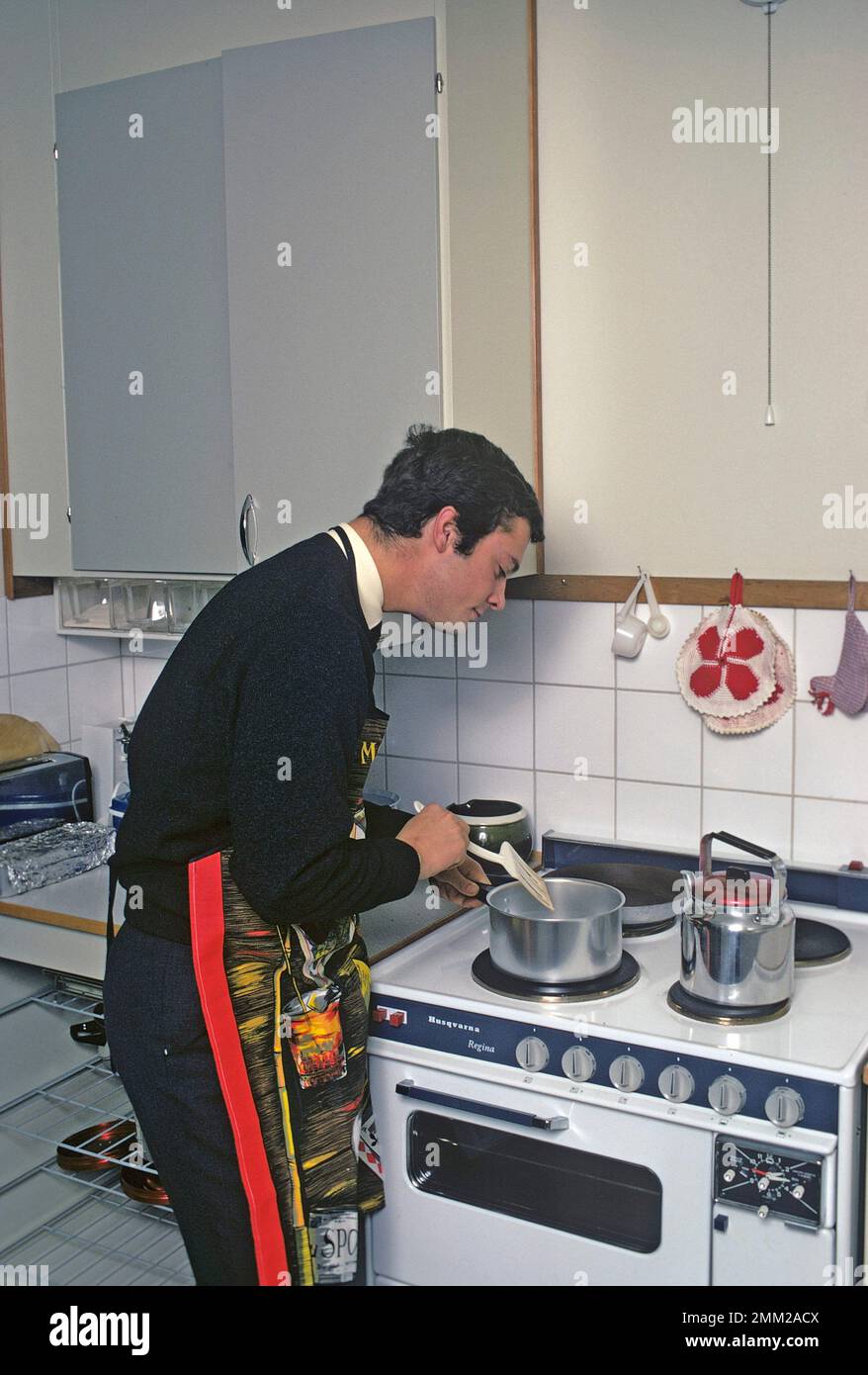 Carl XVI Gustaf, König von Schweden. Geboren am 30. april 1946. Als Kronprinz in seiner Studentenwohnung und Küche, während er in Uppsala studiert. Er steht neben dem Küchenherd und trägt eine Schürze und gibt vor, etwas zu kochen, aber es gibt kein Essen im Kochtopf. 1968 Stockfoto