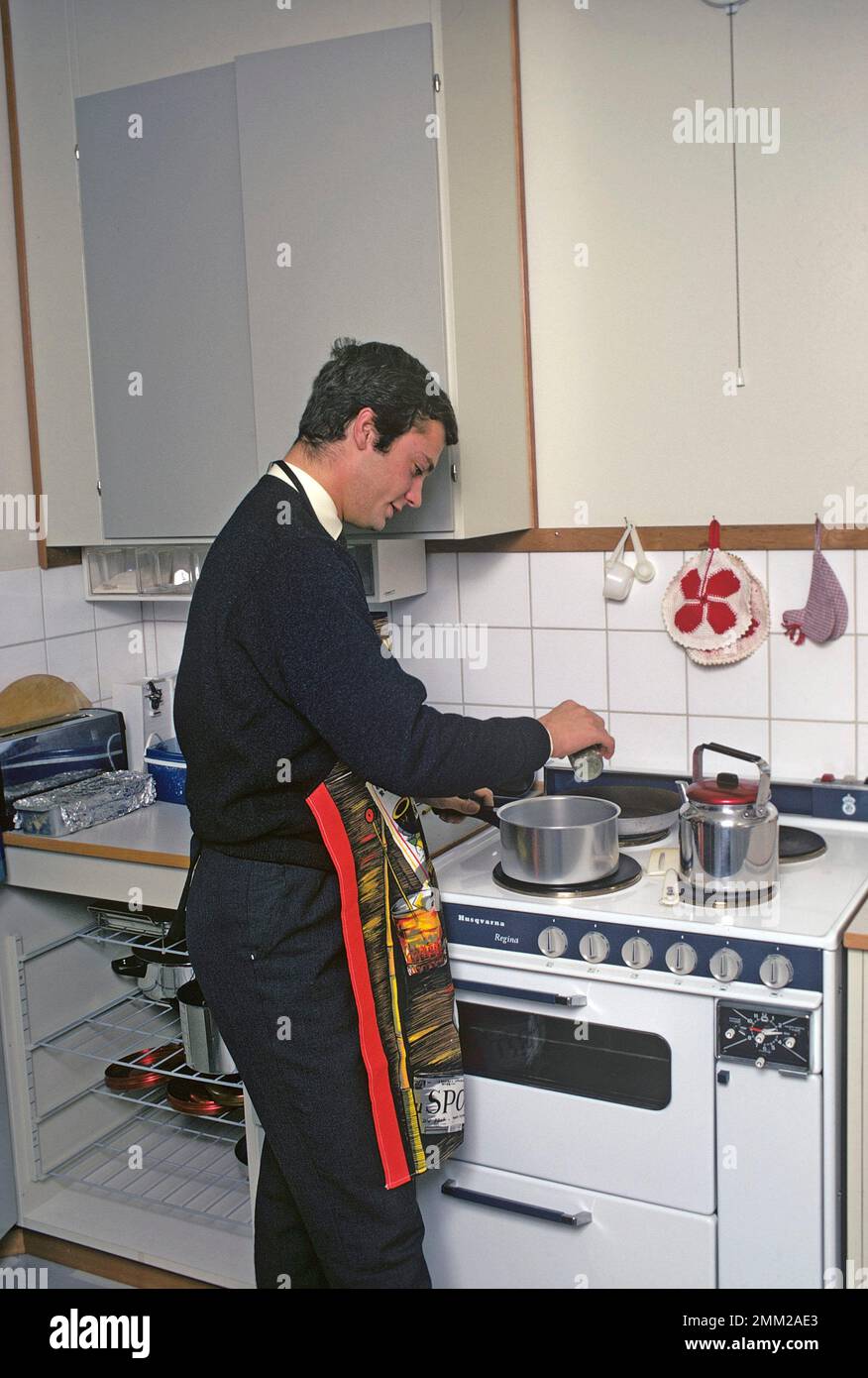 Carl XVI Gustaf, König von Schweden. Geboren am 30. april 1946. Als Kronprinz in seiner Studentenwohnung und Küche, während er in Uppsala studiert. Er steht neben dem Küchenherd und trägt eine Schürze und gibt vor, etwas zu kochen, aber es gibt kein Essen im Kochtopf. 1968 Stockfoto