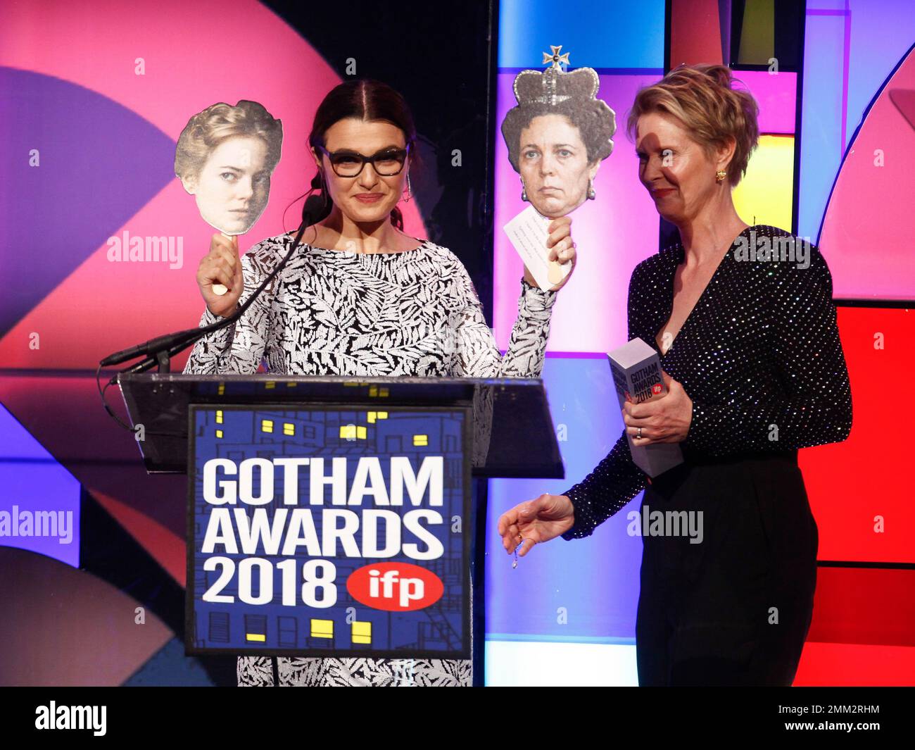 Actress Rachel Weisz, left, holds photos of her costars Emma Stone and
