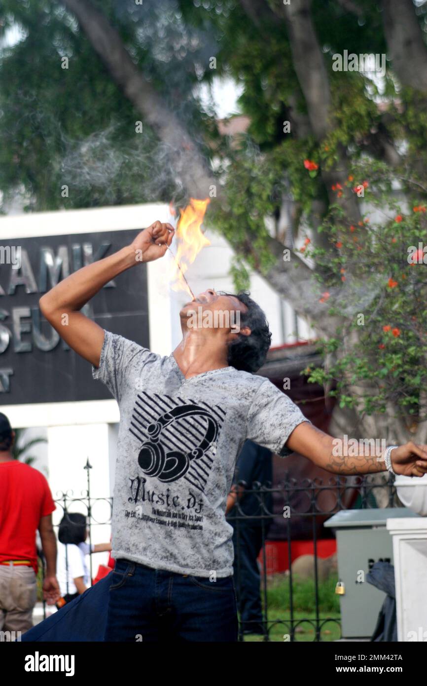 Ein Mann aus indonesien zieht eine gefährliche Attraktion an, indem er ihm Feuer in den Mund steckt Stockfoto