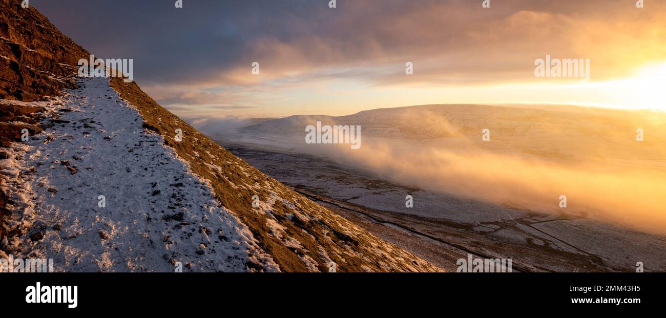 Im Yorkshire Dales National Park, England, könnt ihr den letzten verschneiten Pfad zum Gipfel des Pen-y-ghent bei Sonnenaufgang mit Nebel und Schnee bestaunen Stockfoto
