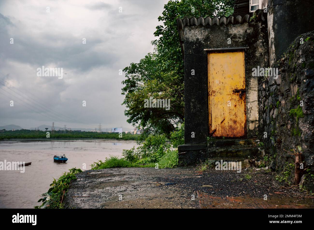 Eine kleine mysteriöse Tür zu einem Haus am Ufer eines Flusses. Eine gelbe Tür. Stockfoto