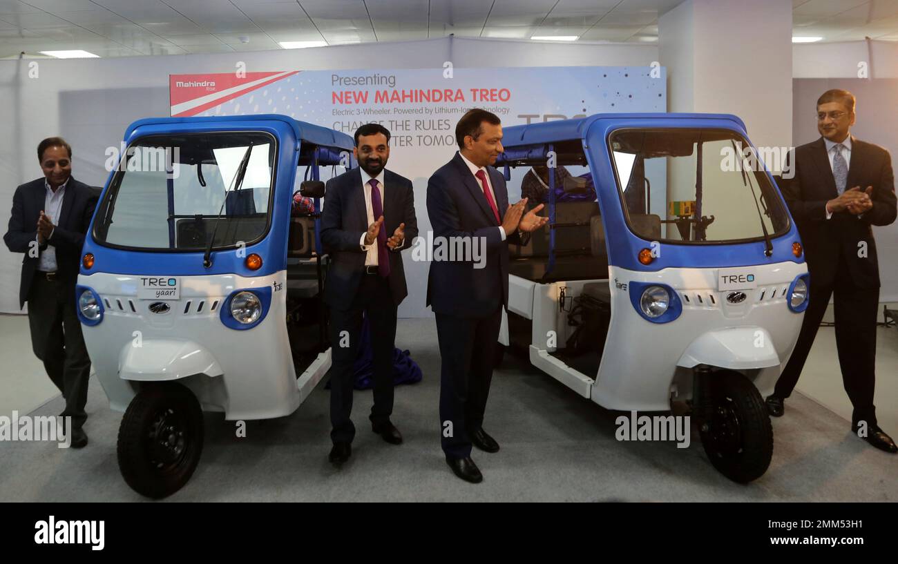 Mahindra Electric Chief Executive Officer Mahesh Babu, center left, and Mahindra and Mahindra Ltd. Managing Director Pawan Goenka, center right, applaud after unveiling Treo, the three-wheeler electric vehicles, at the company's manufacturing facility in the outskirts of Bangalore, India, Thursday, Nov. 15, 2018. Mahindra Electric, a part of the US$ 20.7 billion Mahindra Group, inaugurated company's new Electric Technology Manufacturing Hub on Thursday. (AP Photo/Aijaz Rahi) Stockfoto