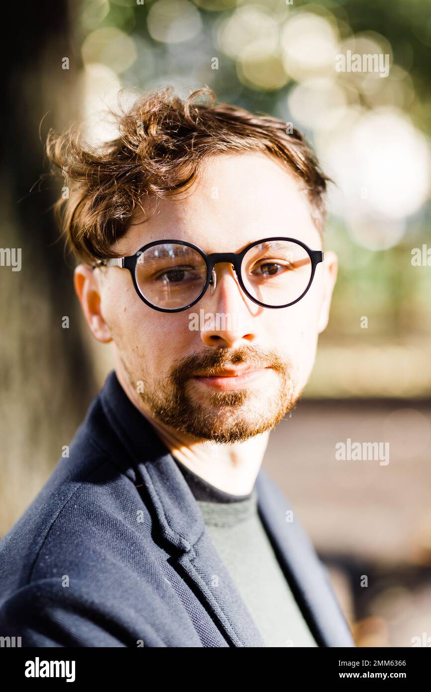 Stilvoller, lockiger Mann mit Brille im Park Stockfoto