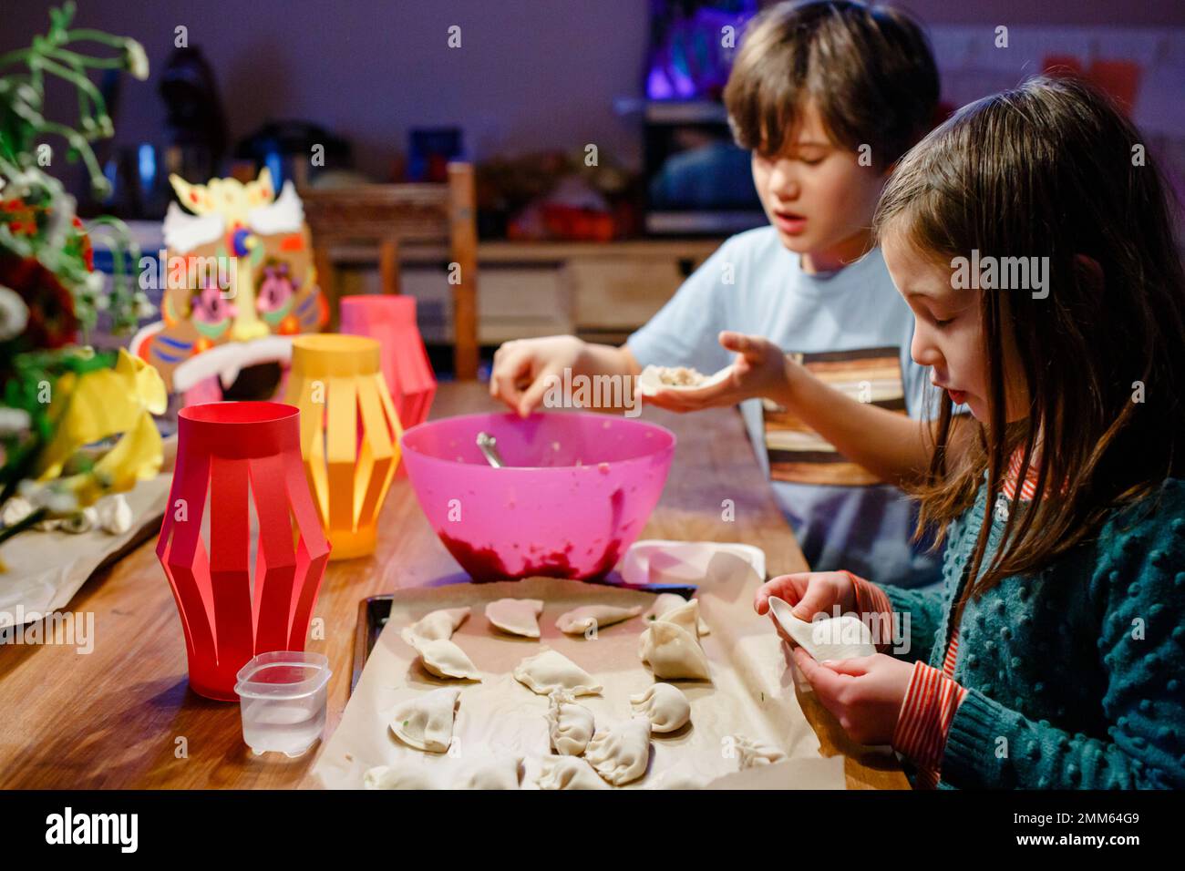 Zwei Kinder sitzen am Tisch, um Knödel zum Mondneujahr zusammenzulegen Stockfoto