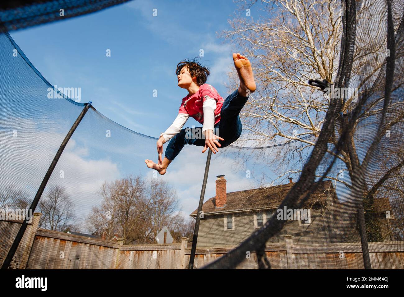 Ein glücklicher Junge springt draußen auf dem Trampolin Stockfoto
