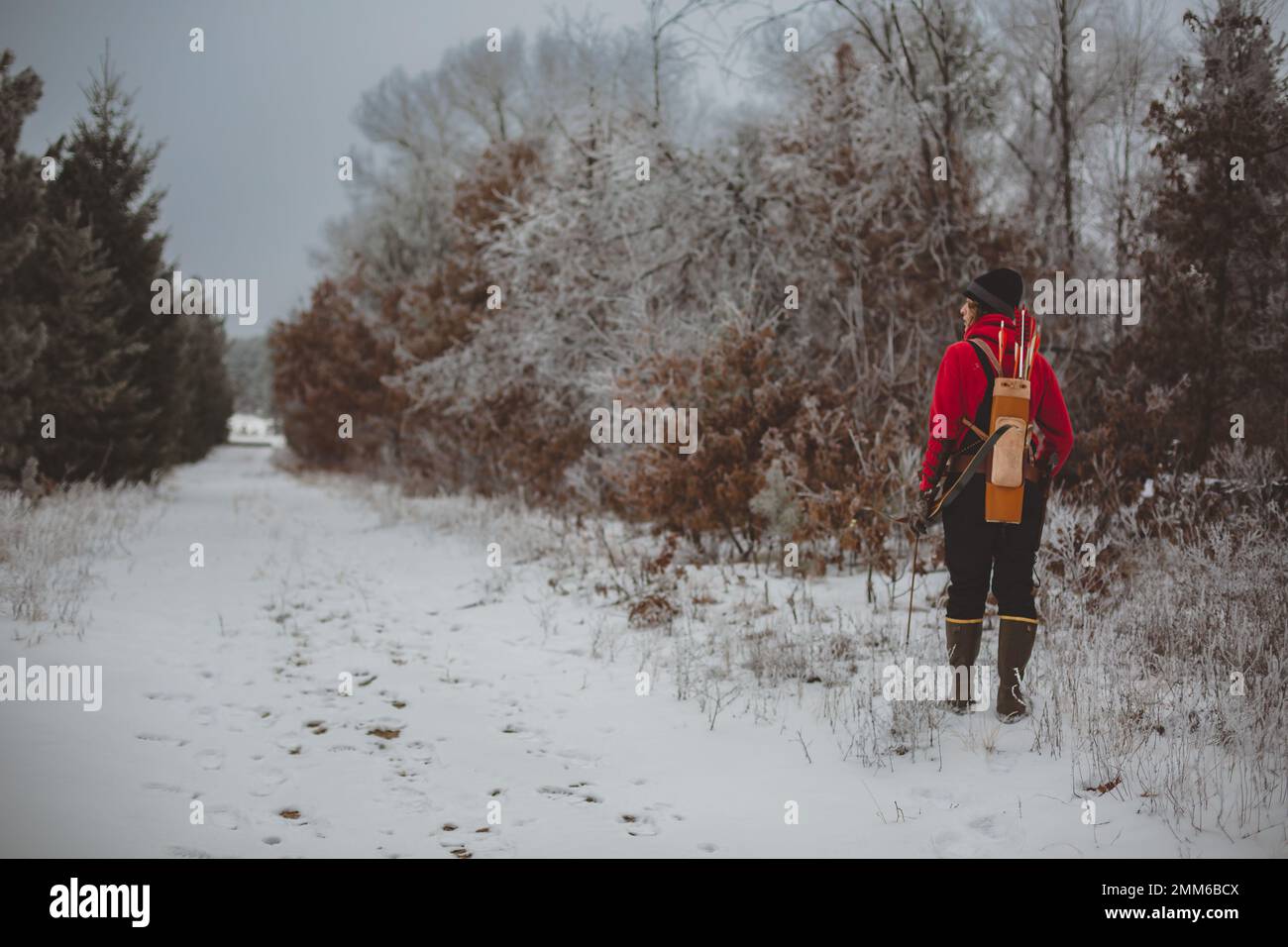 Junger Mann mit Bogen und Köcher entlang des bewaldeten Weges Stockfoto