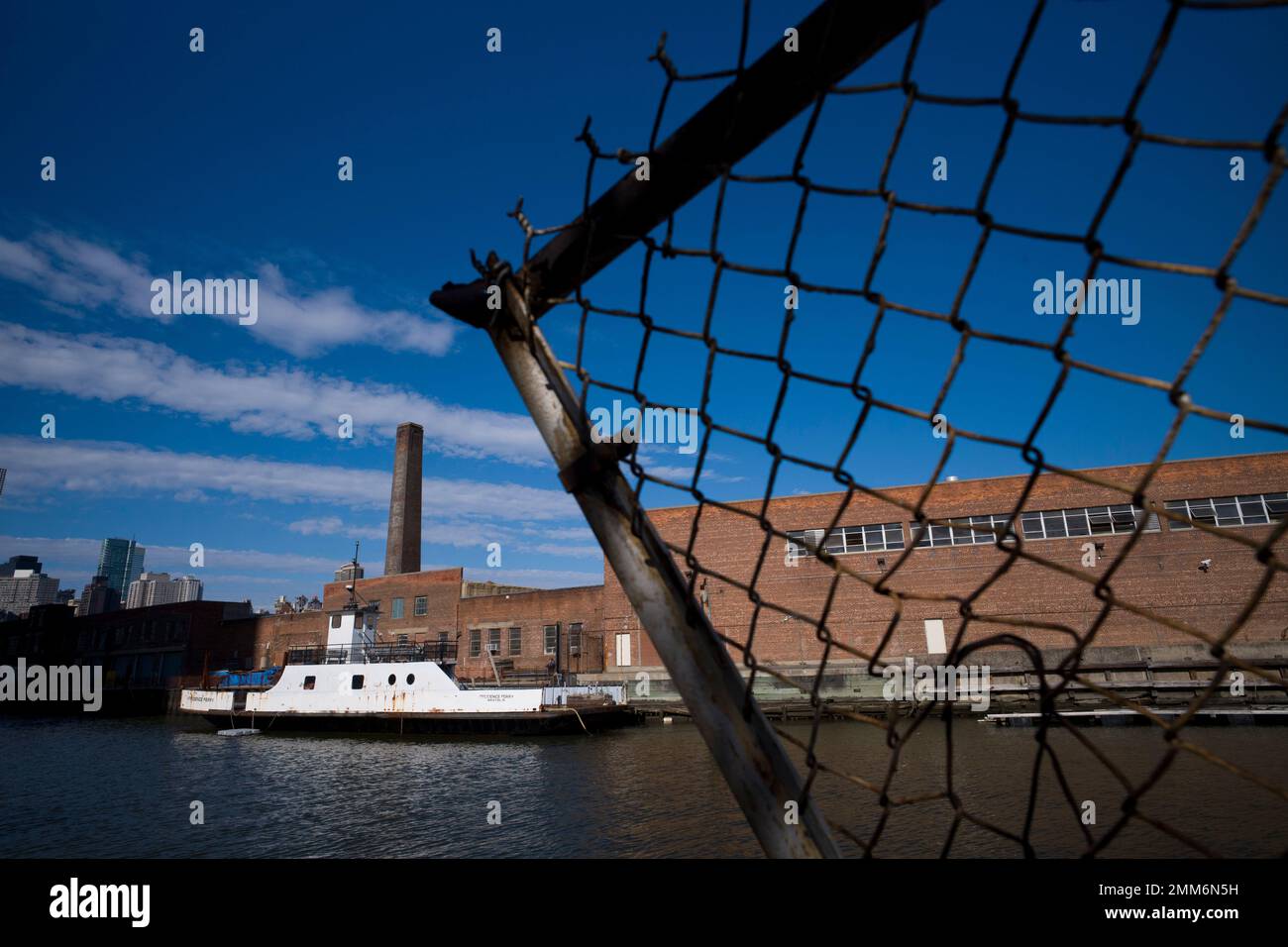 A rusting ferryboat is docked next to an aging industrial warehouse on