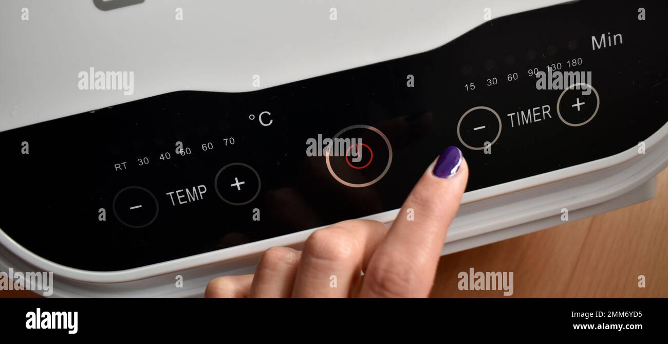 Weibliche Hand, die Temperatur und Zeit am Gerät steuert Stockfoto