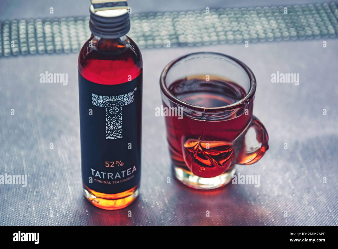 Originaler Tatra-Tee in einer kleinen Flasche und einem halben Glas auf einem Küchentisch Stockfoto