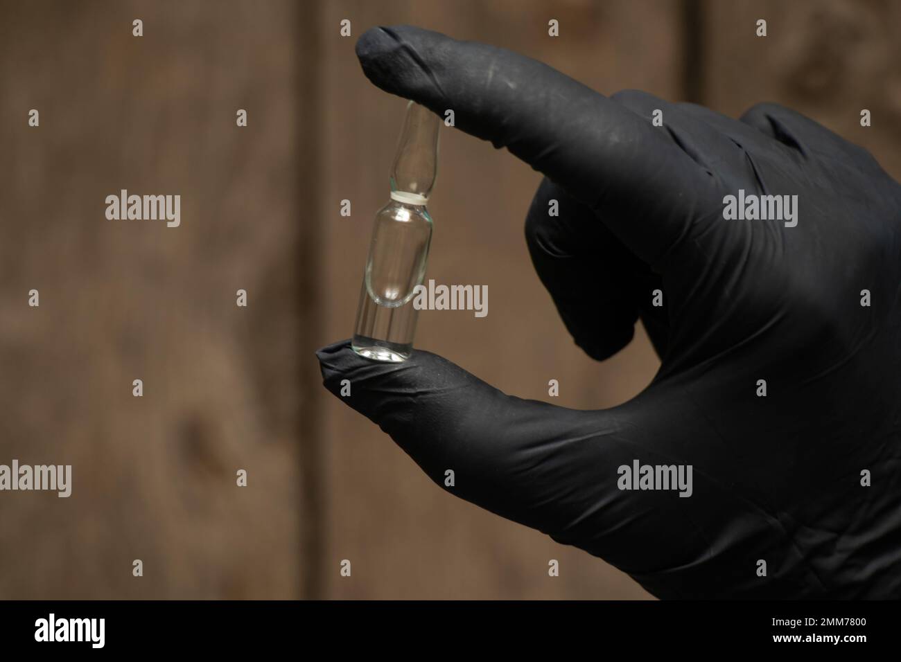 Die Hand in Handschuhen hält eine Ampulle mit Medikamenten Stockfoto