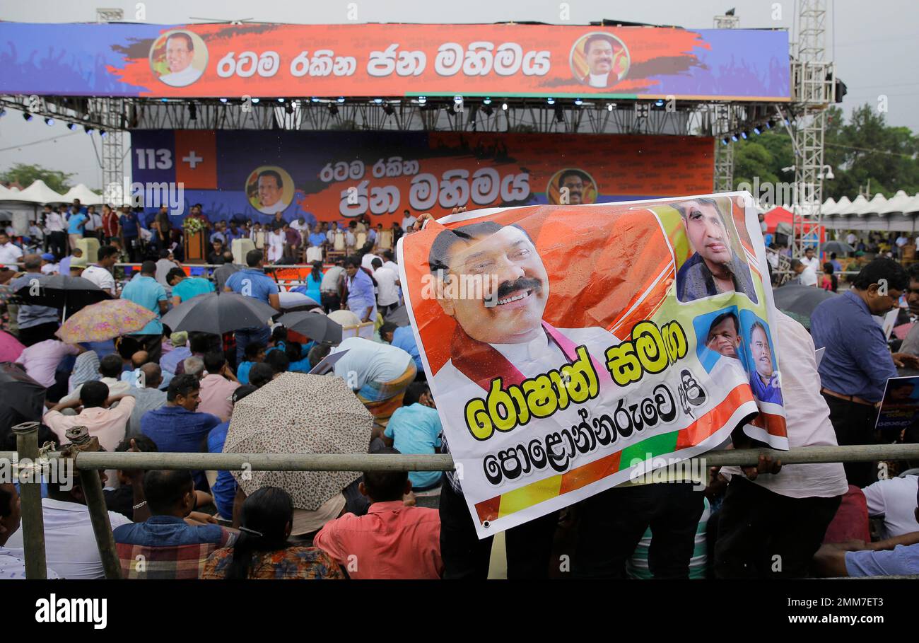 Supporter of Sri Lankan president Maithripala Sirisena and his newly appointed prime minister Mahinda Rajapaksa attend a rally held out side the parliamentary complex as police officer tries to control the crowd in Colombo, Sri Lanka, Monday, Nov. 5, 2018. Banner in Sinhalese reads" Polonnaruwa people with Roshan" (AP Photo/Eranga Jayawardena) Stockfoto