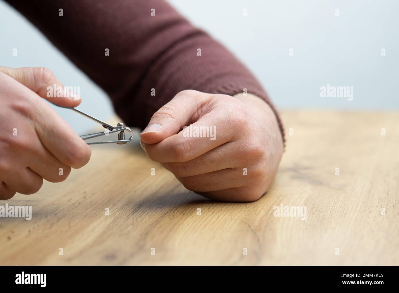 Nahaufnahme von männlichen Händen, die Fingernägel schneiden. Ein junger gutaussehender Mann, der sich die Fingernägel schneidet Stockfoto