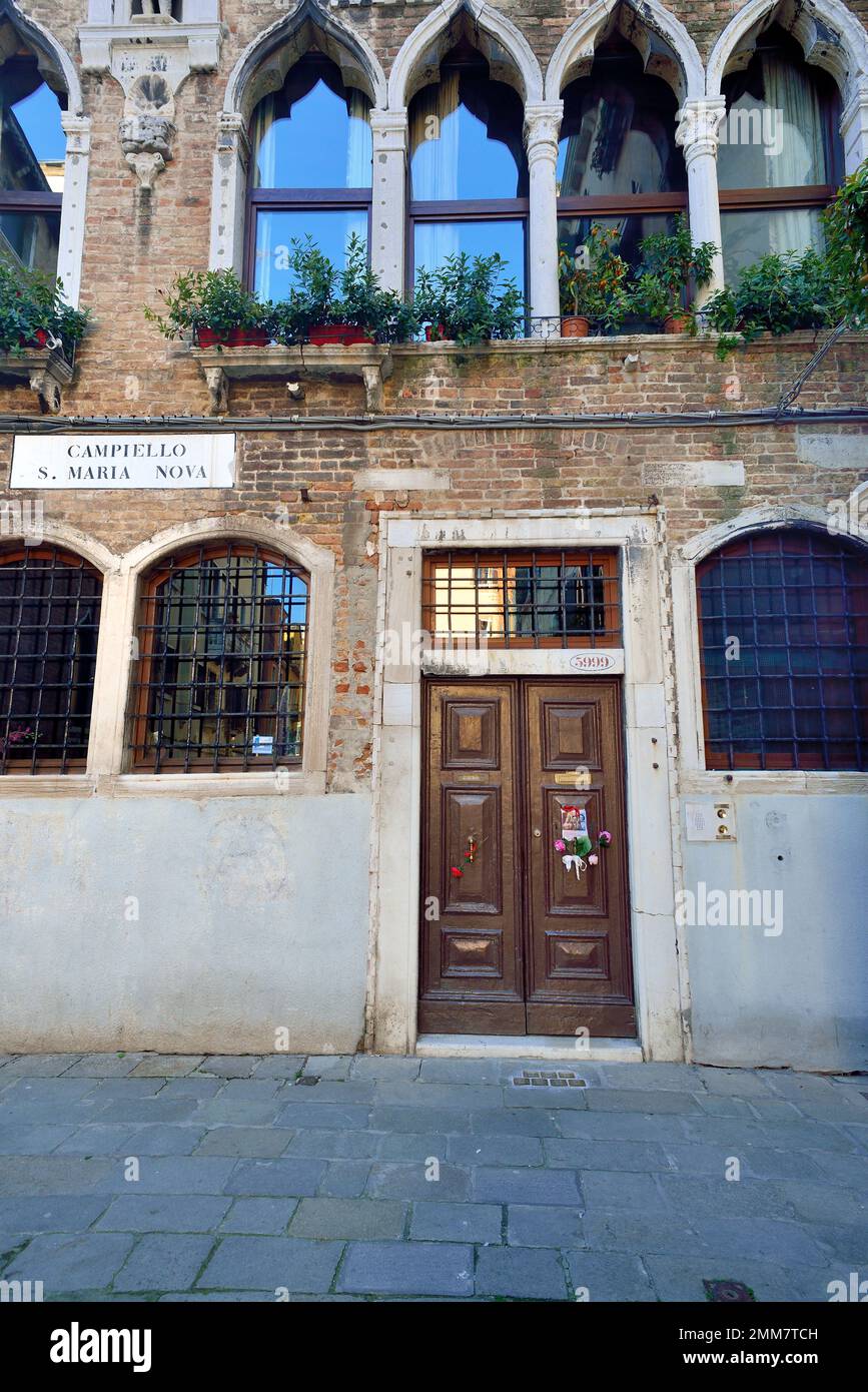 Am Holocaust-Gedenktag 2023 steckte eine anonyme Hand das Bild von drei Kindern und ein paar Blumen an die alte Tür, Nummer 5999 Cannaregio, in Venedig. Die Kinder wurden 1943 mit ihren Eltern und ihrem einjährigen Bruder nach Auschwitz deportiert. Sie waren 14, 10, 7 Jahre alt. Sie wurden am 26. Februar 1944 in Auschwitz mit ihrem einjährigen Bruder getötet. Vor einigen Jahren wurden 7 „Steine“ am Eingang ihres Hauses platziert. Auf dem Foto steht: " Anna, Guido und Giorgia Dina. Leone war ein Jahr alt und wir werden nie wissen, welches Gesicht er hatte. Stockfoto