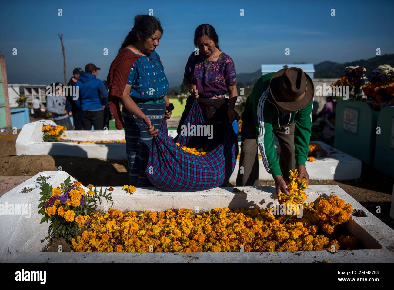 People decorate a relative's tomb with flowers as part of Day of the Dead celebrations in Santiago Sacatepequez, Guatemala, Thursday, Nov. 1, 2018. (AP Photo/Oliver de Ros) Stockfoto