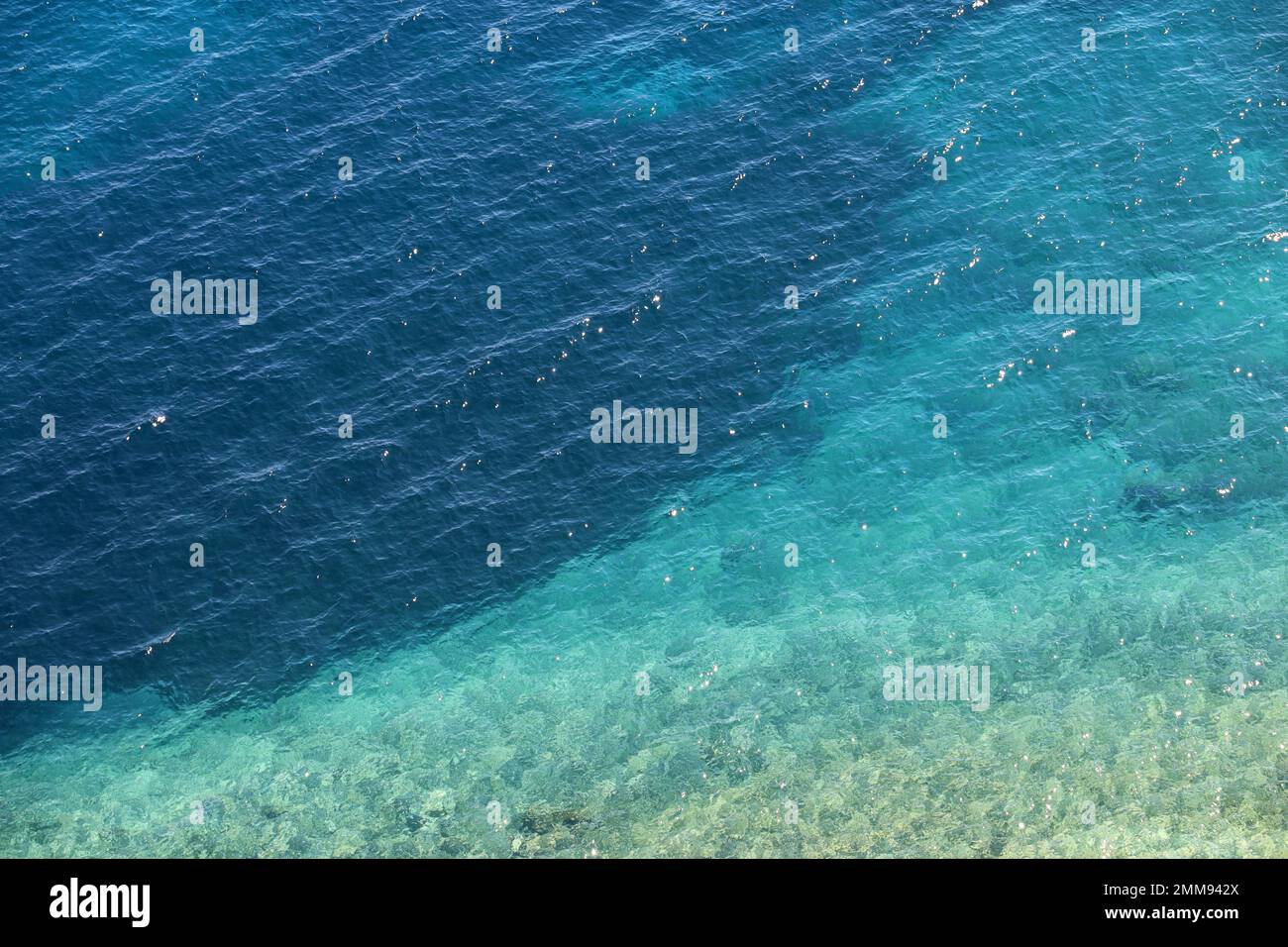 Azurblaue Wassertextur, transparente Meeresoberfläche mit felsigem Boden. Luftaufnahme, natürlicher türkisfarbener Hintergrund Stockfoto