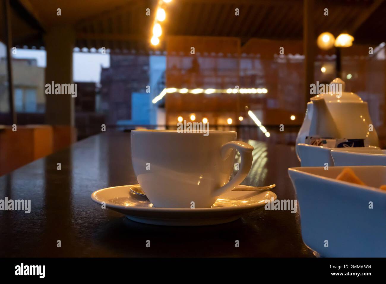 Wunderschöner Blick auf das Restaurant im Jodhpur Rajasthan, Indien. Weiße Tassen, Geschirr und Teekanne mit Reflektoren von dekorierten Lichtern auf dem glänzenden Tisch Stockfoto