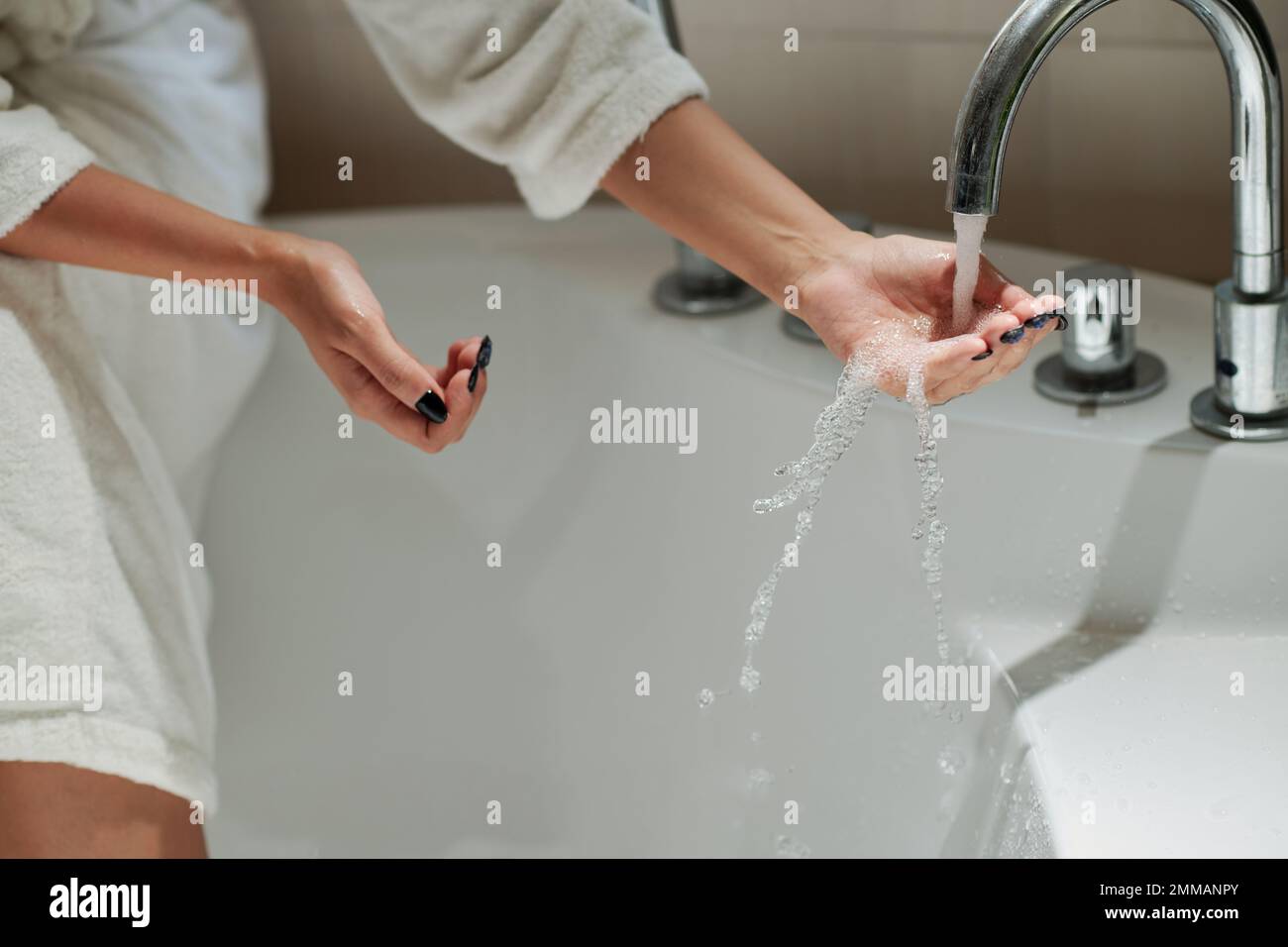 Frau im Bademantel, die die Badewanne mit heißem Wasser füllt Stockfoto