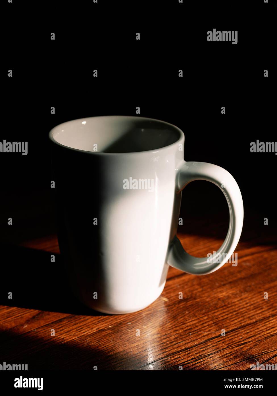 Leere weiße Keramik-Kaffeetasse im Schatten auf einem Restauranttisch. Stockfoto