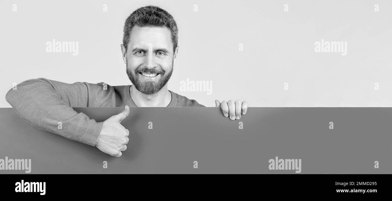 Mann Gesicht Porträt, Banner mit Kopieraum. Glücklicher Mann hinter leerem Papier Banner mit Kopieraum für Job-Angebot zeigen Daumen nach oben, Vorschlag. Stockfoto