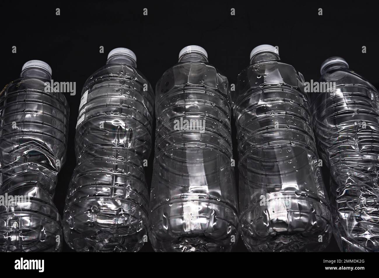 Leere Kunststoff-Wasserflaschen recyceln Material reduzieren Abfall auf schwarzem Hintergrund Stockfoto