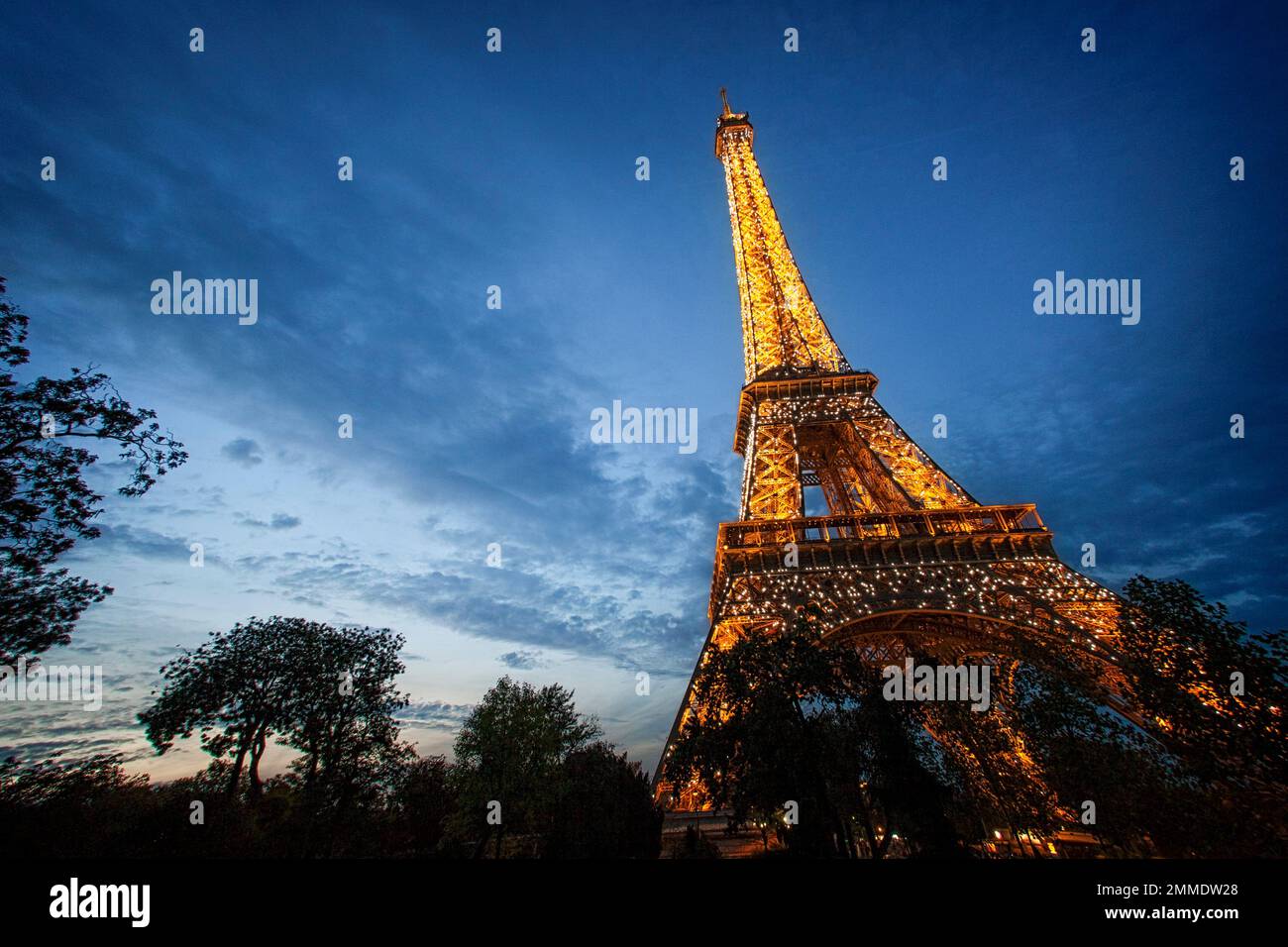 Der Eiffelturm leuchtet in der Abenddämmerung in Paris, Frankreich. Stockfoto