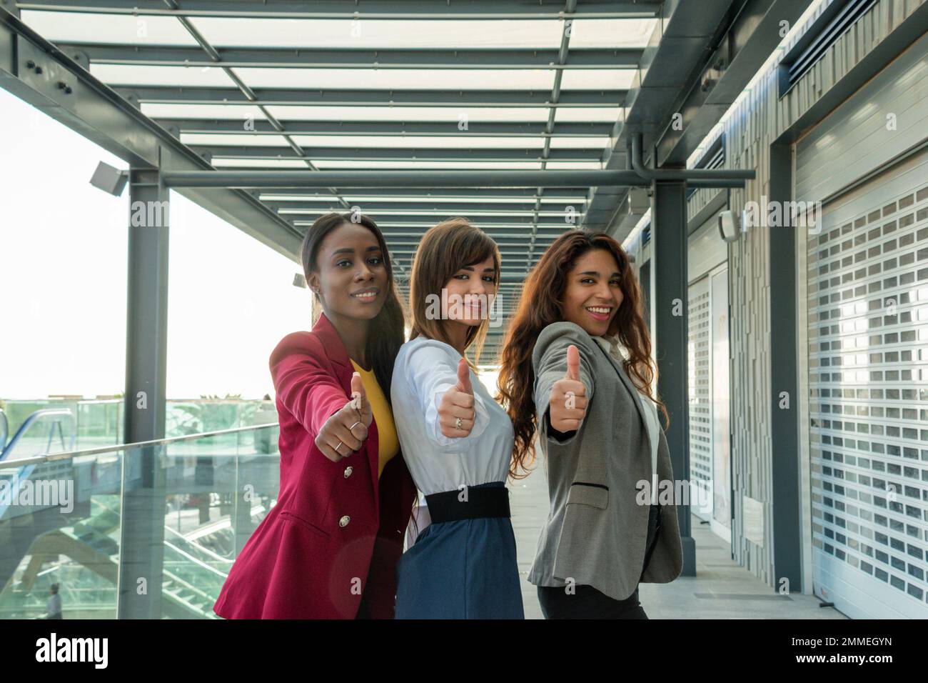 Drei junge Geschäftsfrauen mit Daumen nach oben für Geschäftserfolg. Sie sehen sehr glücklich aus Stockfoto