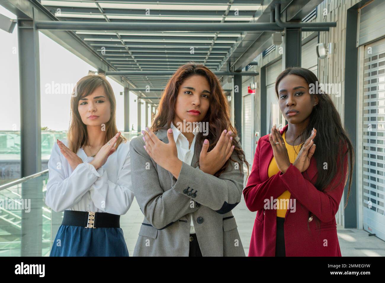 Drei Frauen mit verschränkten Armen unterstützen die Bewegung „Break the Bias“ für den Internationalen Frauentag Stockfoto
