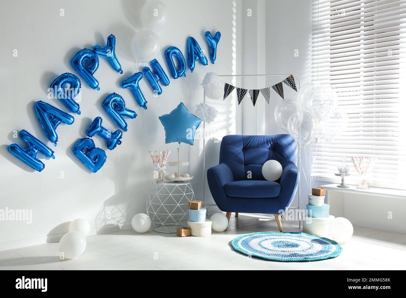 Phrase HAPPY BIRTHDAY aus blauen Ballonbuchstaben im dekorierten Zimmer Stockfoto