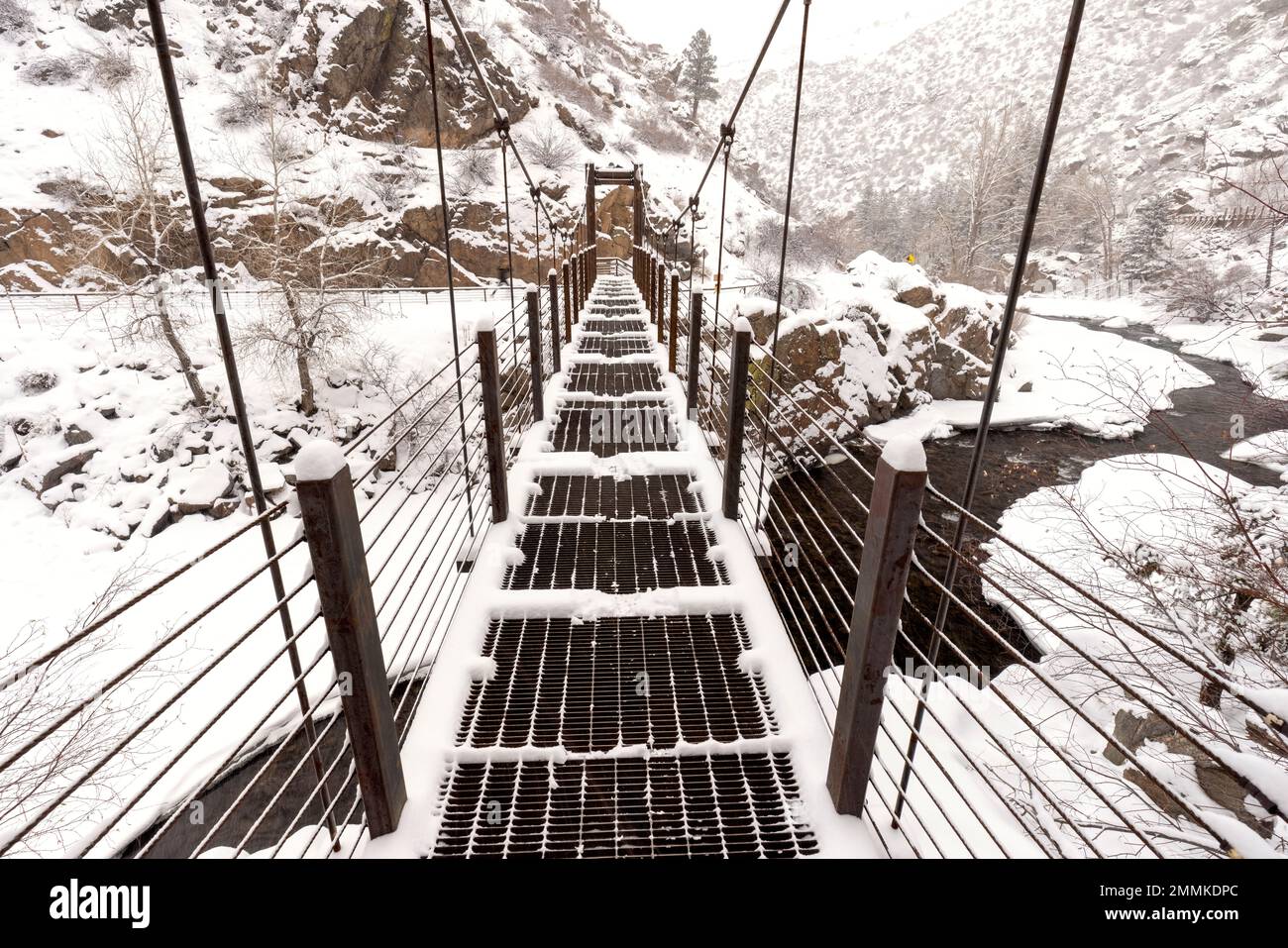 Schneebedeckte Hängebrücke auf dem Welch Ditch Trail im Clear Creek Canyon. Teil des Peaks to Plains Trail in der Nähe von Golden, Colorado, USA Stockfoto