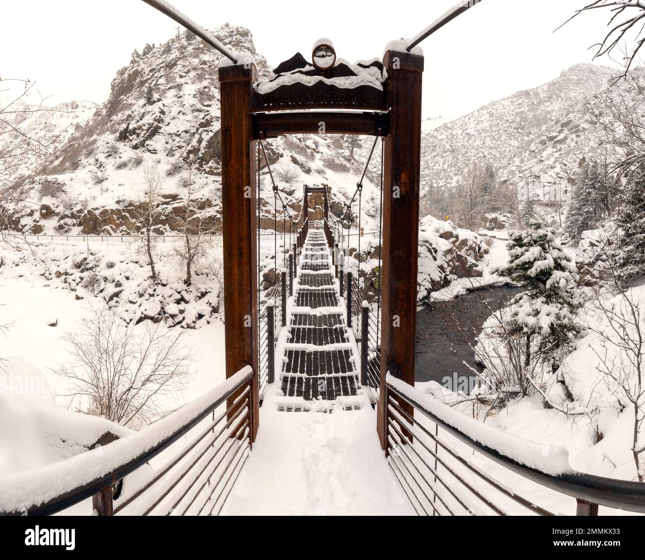 Schneebedeckte Hängebrücke auf dem Welch Ditch Trail im Clear Creek Canyon. Teil des Peaks to Plains Trail – in der Nähe von Golden, Colorado, USA [Panorama I Stockfoto