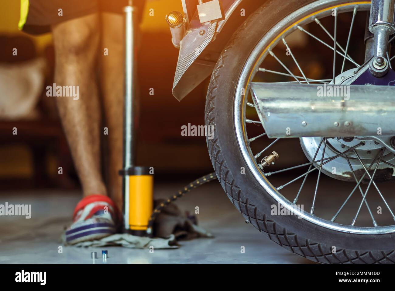Der junge Mann überprüft den Druck des Gasgenerators und pumpt den Reifen  auf dem Motorrad mit der Fußbodenpumpe auf. Personen, die den Luftdruck  prüfen und den Reifendruck auffüllen Stockfotografie - Alamy