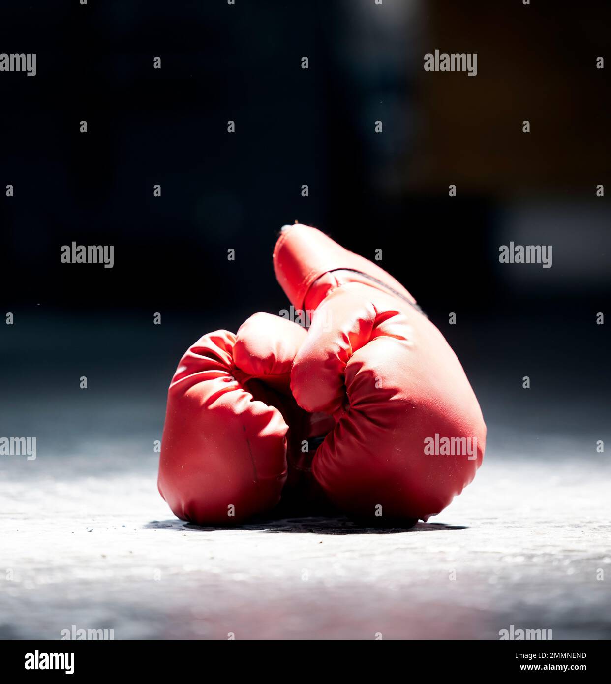 Boxhandschuhe, Boden- und Sportschuhe auf dunklem Hintergrund im Studio für Gesundheit, Wettkampf oder Sport. Fitness-, Leder- und schützende Sportbekleidung für einen Stockfoto