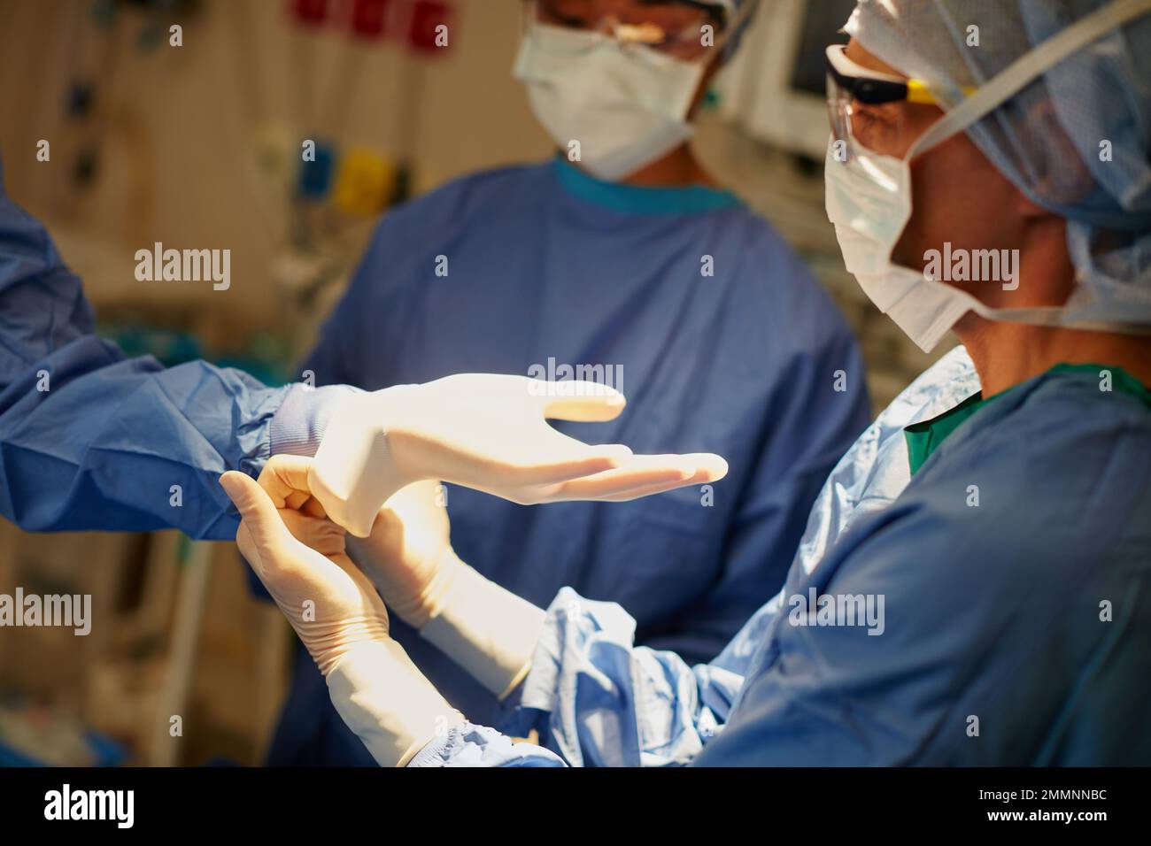 Einander bei der Operationsvorbereitung eine helfende Hand zu geben. Chirurgen, die Operationshandschuhe zur Vorbereitung auf eine Operation anziehen. Stockfoto