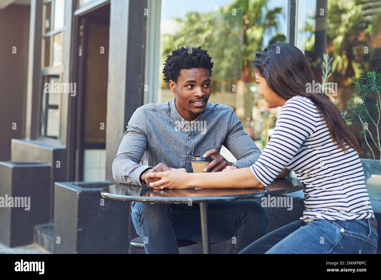 Ich bin froh, dass du mich auf einen Kaffee eingeladen hast. Ein junges Paar auf einem Kaffee-Date in einem Straßencafé. Stockfoto