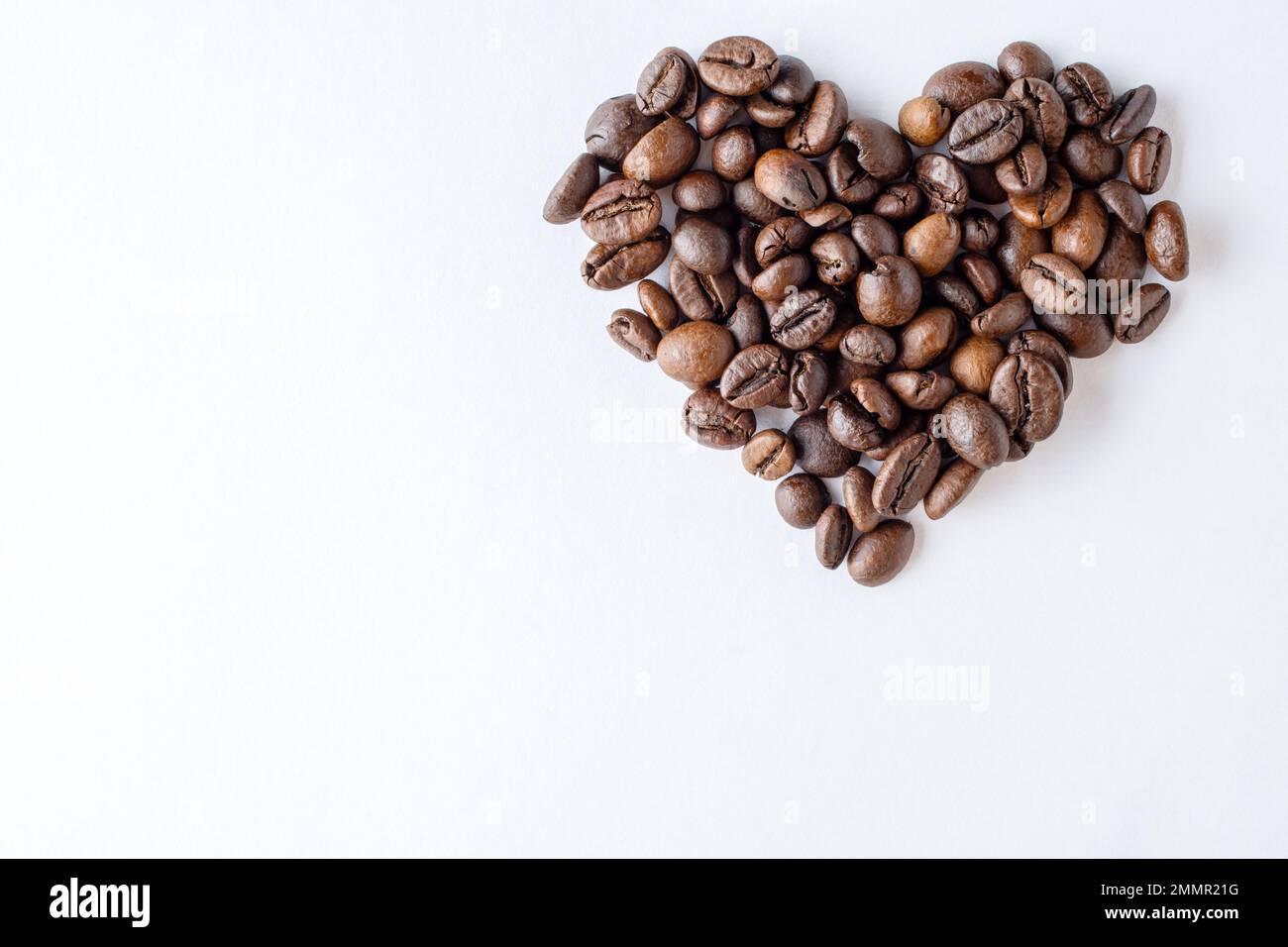 Symbol der Liebe zum Kaffee. Herzform aus Kaffeebohnen auf weißem Hintergrund, Nahaufnahme, Draufsicht, flach liegend, Kopierbereich, Banner Stockfoto