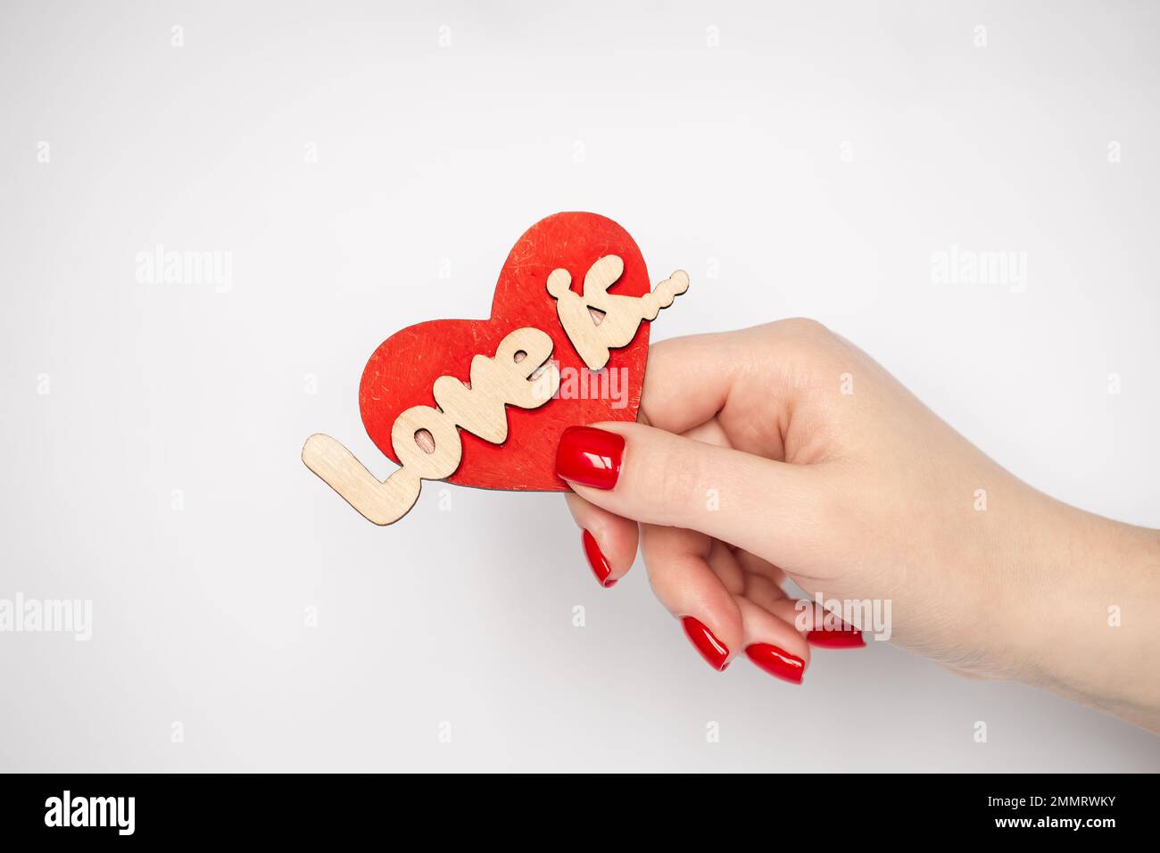 Dekoratives Herz mit der Inschrift Liebe ist in der weiblichen Hand Nahaufnahme. Stockfoto